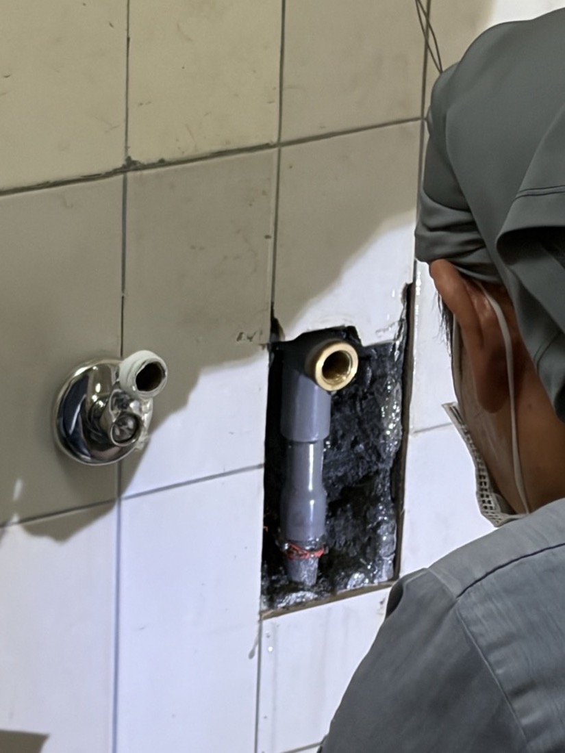漏水查修:地磚切除後露出地下灰色 PVC 給水管與舊有金屬出水接頭,準備重接。