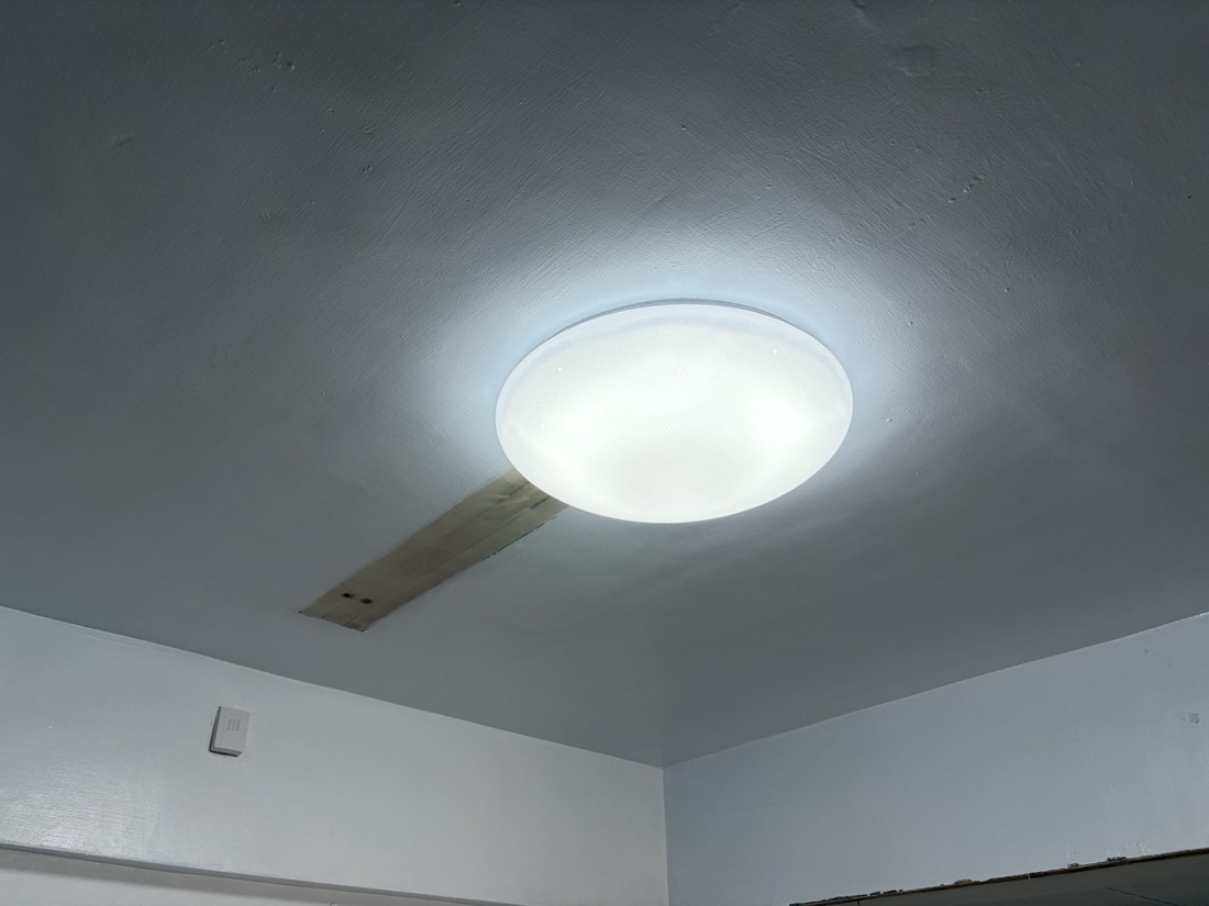 明管配線:天花板新裝大型圓形 LED 吸頂燈,旁可見木板補洞修補之配線通道。