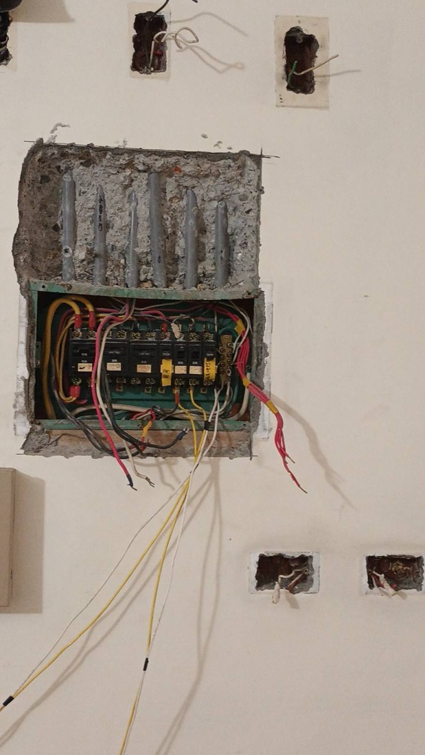 配電盤施作：老屋牆內舊式分電盤拆除更換中，可見原有埋管與電線出口。