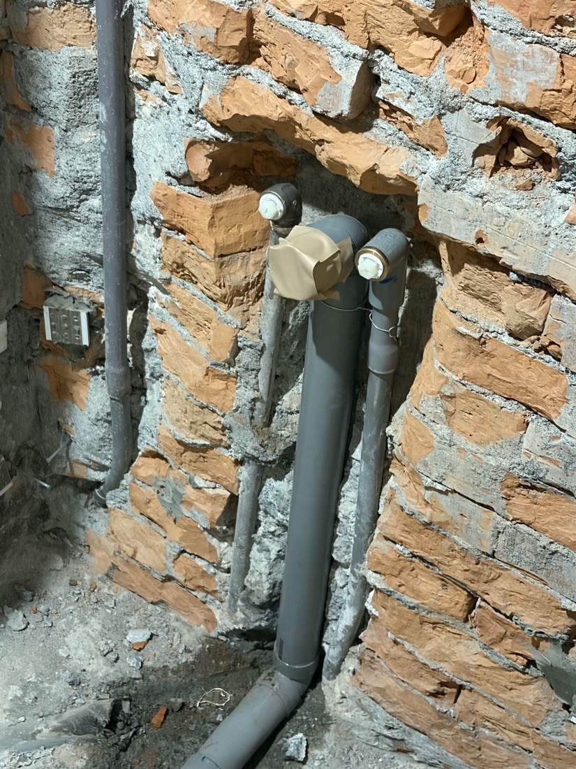 老屋配管:磚牆打鑿後鋪設多支灰色 PVC 給排水管與電氣管,固定後準備粉光封壁。